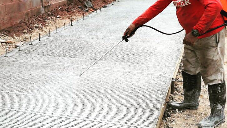 Utilización de curador para garantizar la estabilidad y calidad del concreto en una pavimentación.